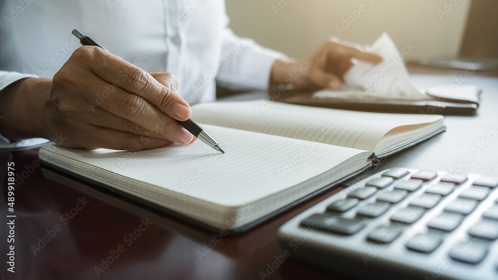 Fototapeta premium Woman with bills and calculator. Woman using calculator to calculate bills at the table in office. Calculation of costs.