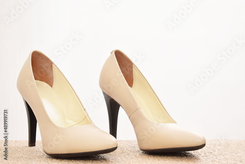 Zapatos de tacón para mujer color beige. Calzado formal para fiesta o trabajo sobre un fondo blanco, espacio para texto al lado derecho.