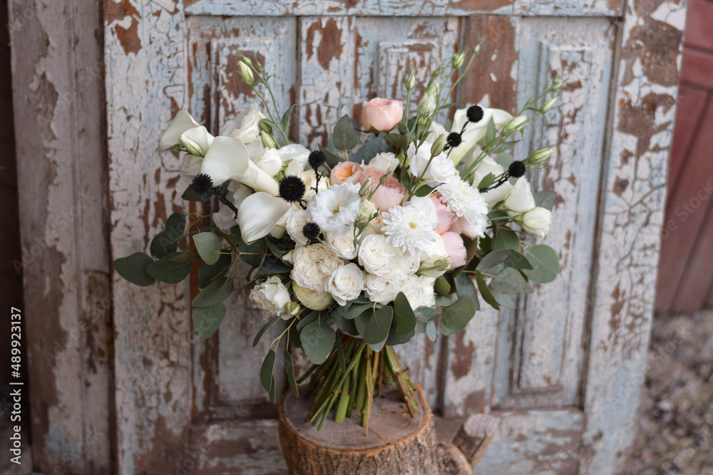 Modern bridal bouquet made from roses, freesia, eustoma and eucalyptus on dark background.