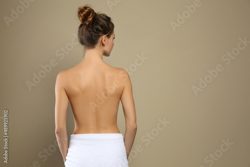 Back view of woman with perfect smooth skin on beige background, space for text. Beauty and body care