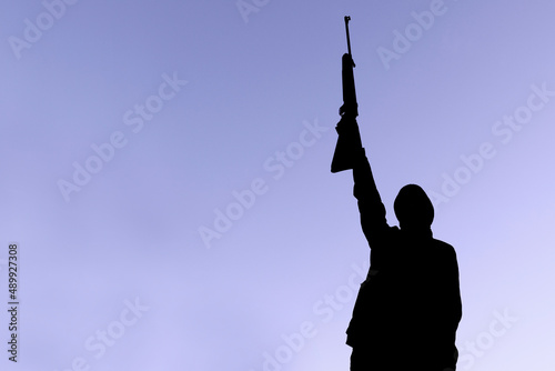 Silhouette of a man with a weapon in his hands against the background of art, lilac sky, the color of the year 2022. The concept of military operations, conflict resolution. Copyspace.