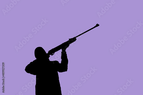 Silhouette of a man with a weapon in his hands against the background of art, lilac sky, the color of the year 2022. The concept of military operations, conflict resolution. Copyspace.