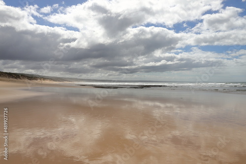 A scenic view on the beach with clouds and reflections.