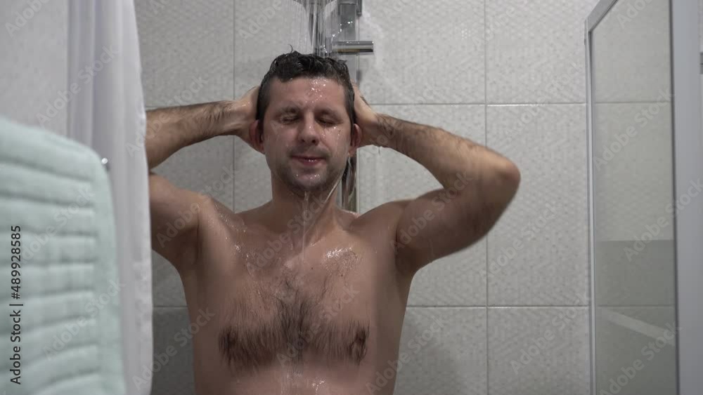 A happy man takes a shower in the morning. Athletic man in the shower A happy man takes a shower in the morning. Athletic man in the shower
