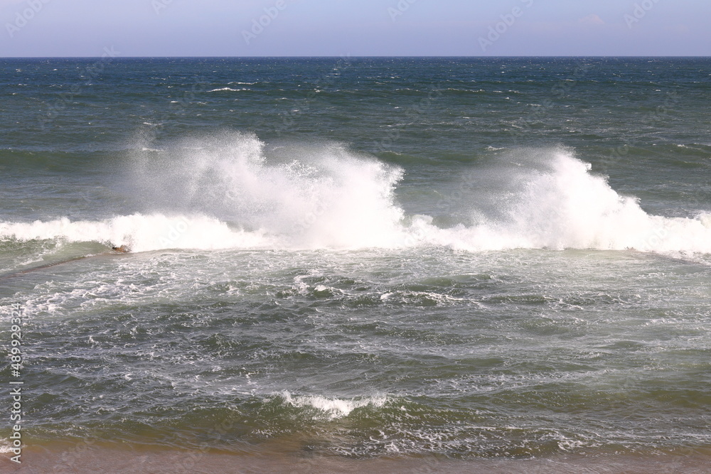 Beautiful waves striking a wall and throwing spray into the wind.