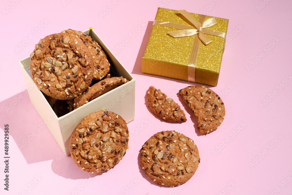Fototapeta premium oatmeal cookie in gift box over pink background with copy space. Gift box of cookies with shadows and sunlight.