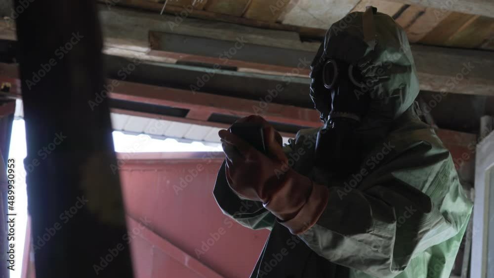 person in protective chemical suit gloves and gas mask checks level of radiation inside abandoned room person in protective chemical suit gloves and gas mask checks level of radiation inside abandoned room