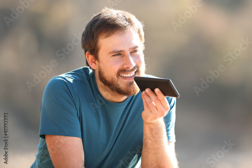 Photos Happy man using voice recognition on cellphone outdoors