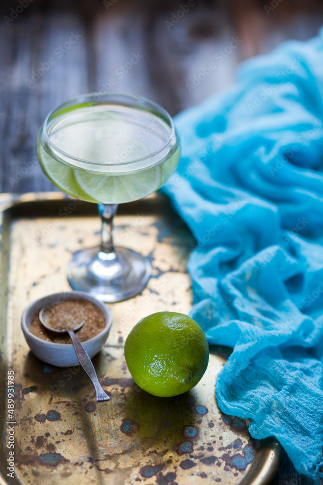 Refreshing cocktail with lime and  sugar cane. Fresh drink. On old wooden background, vintage cooper tray. 