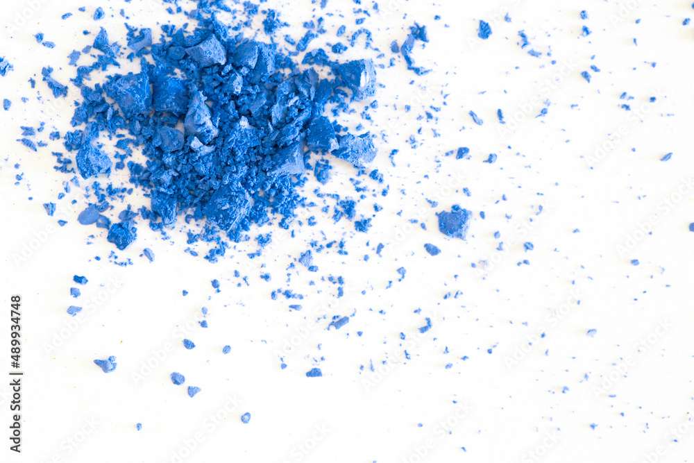 Colored powder on a white background. Blue eyeshadows are scattered and smeared, makeup. Holi Colorful festival of colored paints powders and dust. A holiday of bright colors to entertain people.