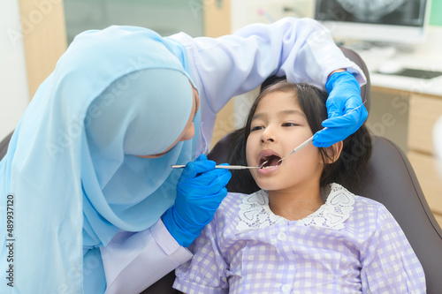 A little cute girl having teeth examined by muslim dentist in dental clinic  teeth check-up and Healthy teeth concept