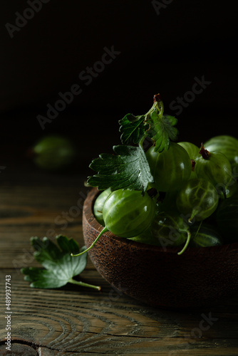 juicy gooseberry berries in a wooden cup on a dark background. High quality photo