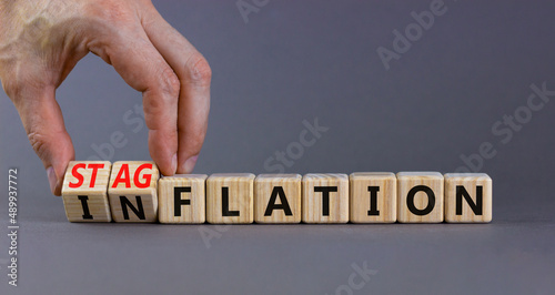 Stagflation or inflation symbol. Businessman turns cubes and changes the concept word inflation to stagflation. Beautiful grey background, copy space. Business stagflation or inflation concept. photo