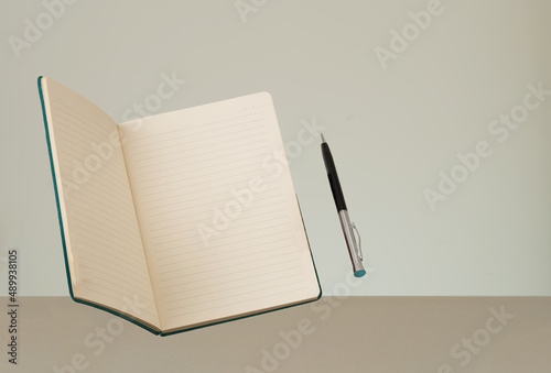 Close up photo of floating notebook and pen. Notebook blank page mockup.