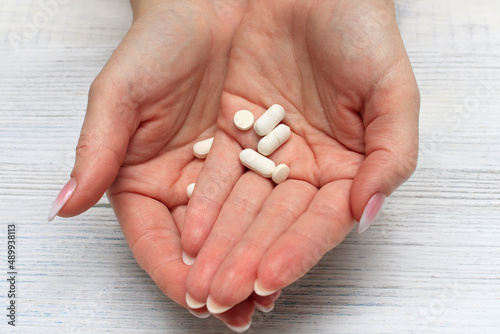 White tablets lying in women's hands. The concept of taking antibiotics, vitamins, medicines