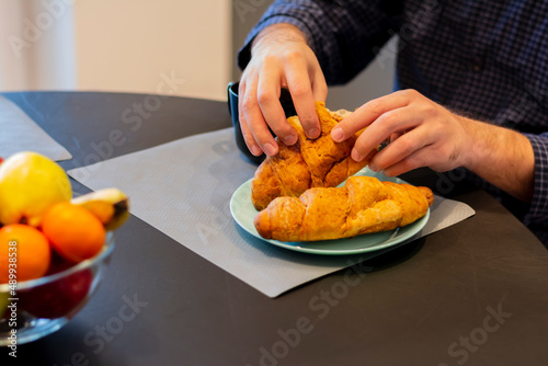 Close-up of a man's hands eating tearing delicious fragrant french croissant diet nutrition meal