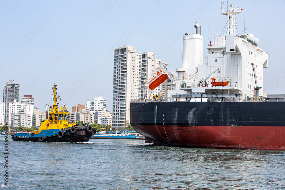 Fototapeta premium tugboat maneuvers a ship at port fo Santos, Brazil