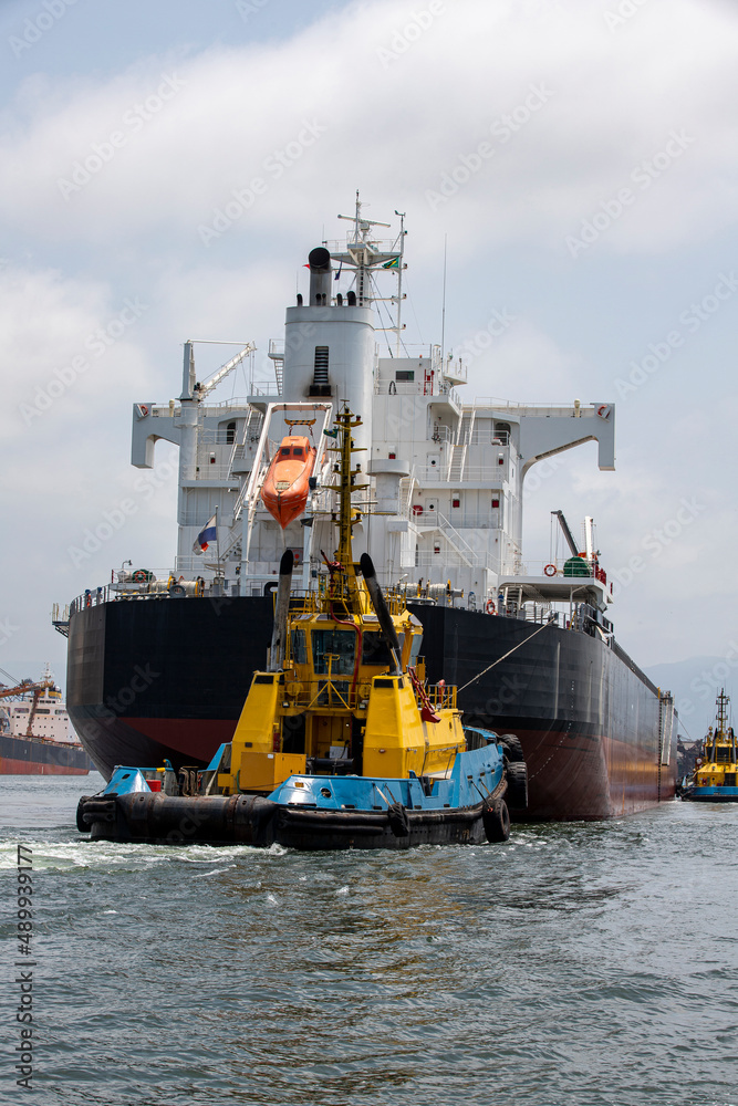 tugboat maneuvers a ship at port fo Santos, Brazil