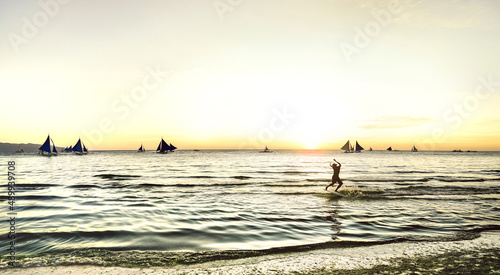 Fototapeta Naklejka Na Ścianę i Meble -  Silhouette of skimboarder at sunset with typical sailing boats at Boracay island - Extreme sport and exclusive travel concept in Philippines - Warm sunshine filtered look