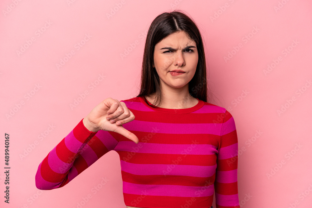 Young caucasian woman isolated on pink background showing thumb down, disappointment concept. Young caucasian woman isolated on pink background showing thumb down, disappointment concept.