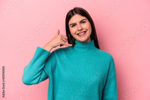 Young caucasian woman isolated on pink background showing a mobile phone call gesture with fingers. © Asier