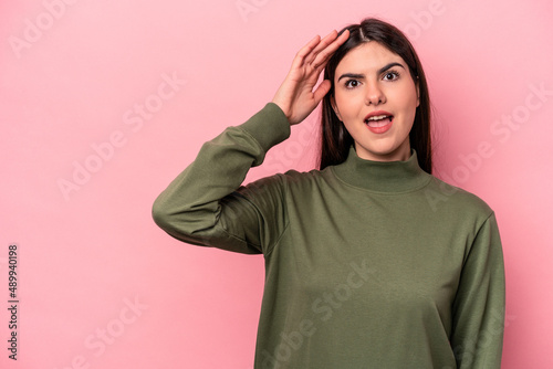 Young caucasian woman isolated on pink background shouts loud, keeps eyes opened and hands tense. © Asier