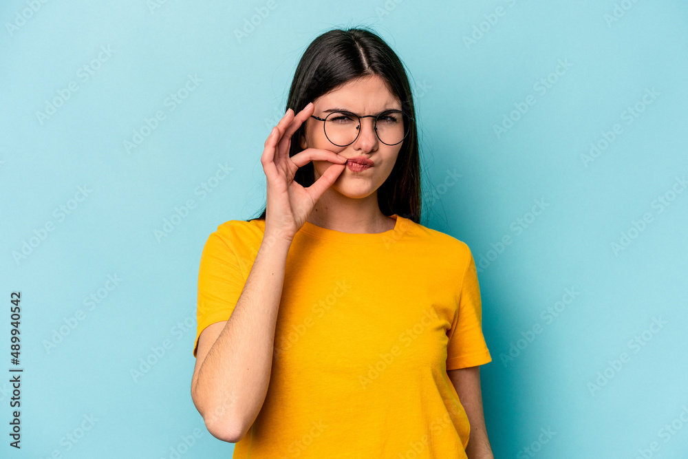 Young caucasian woman isolated on blue background with fingers on lips keeping a secret. Young caucasian woman isolated on blue background with fingers on lips keeping a secret.