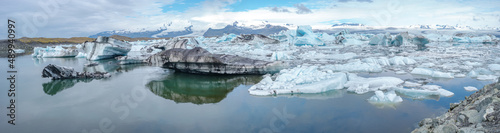 Panoramic view of Glacier Lagoon Jokulsarlon with icebergs and Vatnajokull Glacier tongue, Iceland, summer, with a touristic tour boat and people.
