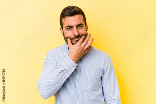 Young caucasian man isolated on yellow background doubting between two options.