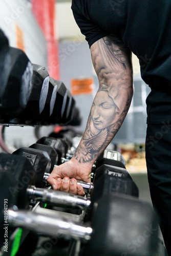 Tattooed man holding hand weights in the gym. Healthy lifestyle, workout concept © Cristian Borrego 