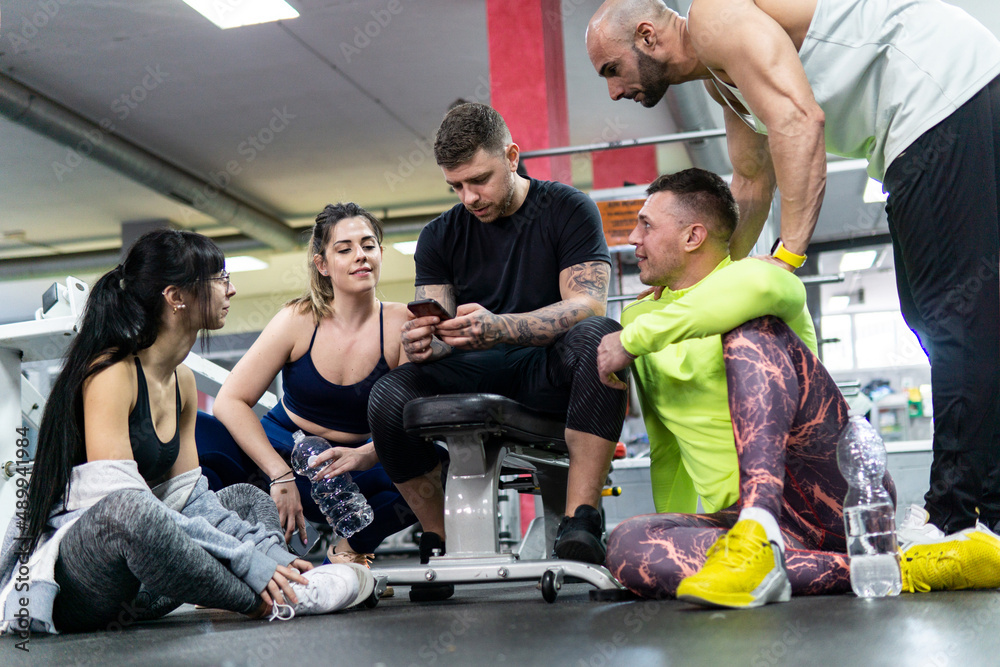Group of friends relaxing and laughing in the gym. Healthy lifestyle, workout concept
