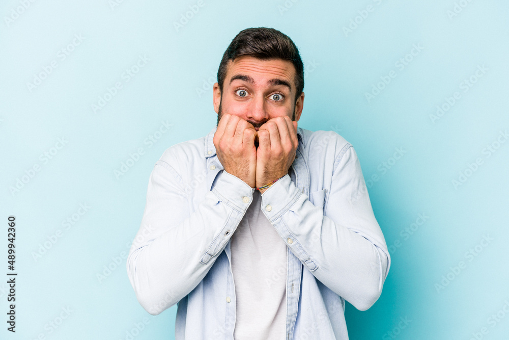 Young caucasian man isolated on blue background biting fingernails, nervous and very anxious. Young caucasian man isolated on blue background biting fingernails, nervous and very anxious.