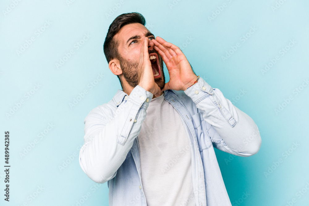 Young caucasian man isolated on blue background shouting excited to front. Young caucasian man isolated on blue background shouting excited to front.