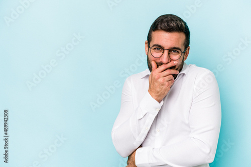 Young caucasian man isolated on blue background laughing happy, carefree, natural emotion.