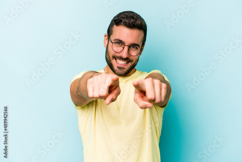 Young caucasian man isolated on blue background pointing to front with fingers.