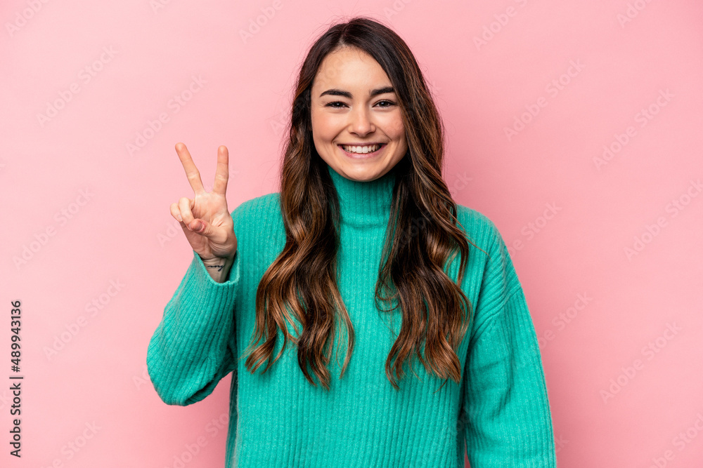 Young caucasian woman isolated on pink background joyful and carefree showing a peace symbol with fingers. Young caucasian woman isolated on pink background joyful and carefree showing a peace symbol with fingers.