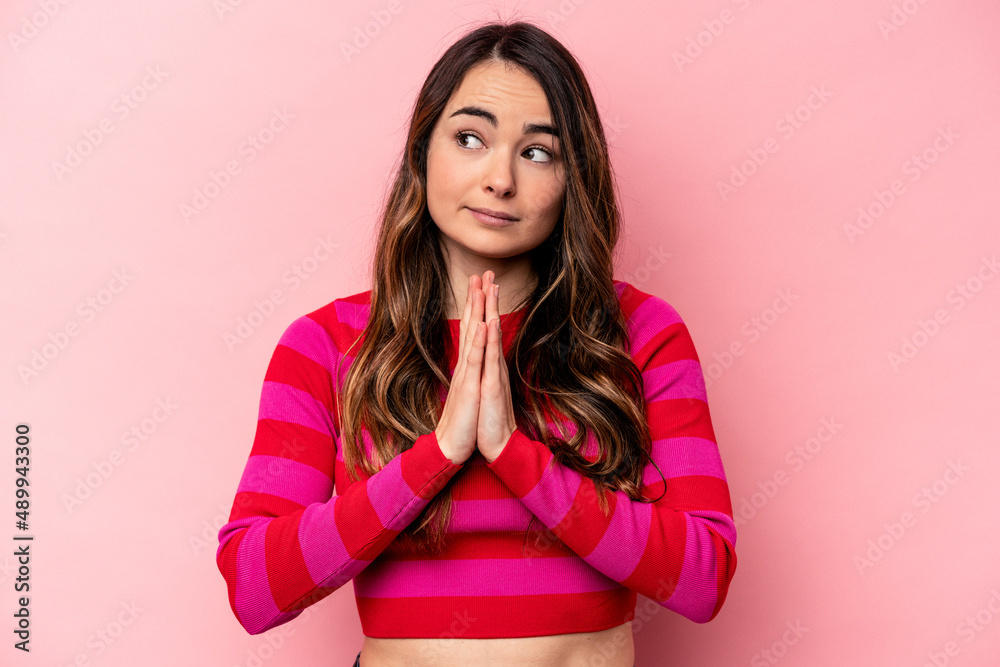 Young caucasian woman isolated on pink background praying, showing devotion, religious person looking for divine inspiration. Young caucasian woman isolated on pink background praying, showing devotion, religious person looking for divine inspiration.