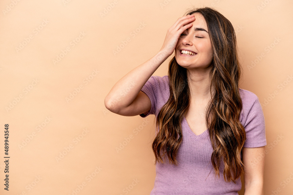 Young caucasian woman isolated on beige background laughing happy, carefree, natural emotion. Young caucasian woman isolated on beige background laughing happy, carefree, natural emotion.