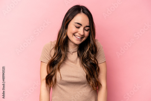 Young caucasian woman isolated on pink background laughs and closes eyes  feels relaxed and happy.