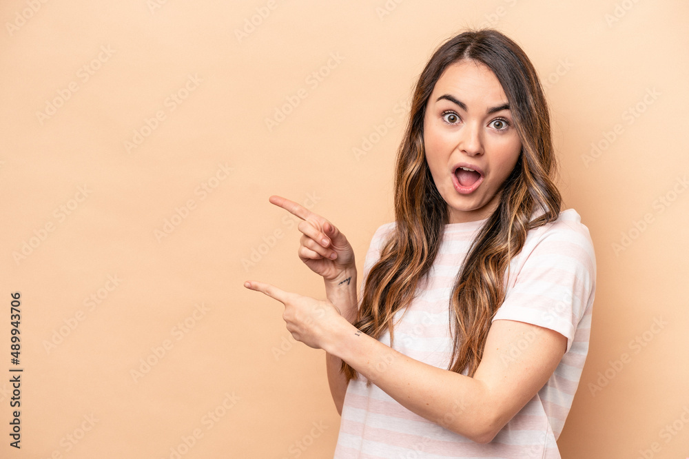 Young caucasian woman isolated on beige background pointing with forefingers to a copy space, expressing excitement and desire. Young caucasian woman isolated on beige background pointing with forefingers to a copy space, expressing excitement and desire.