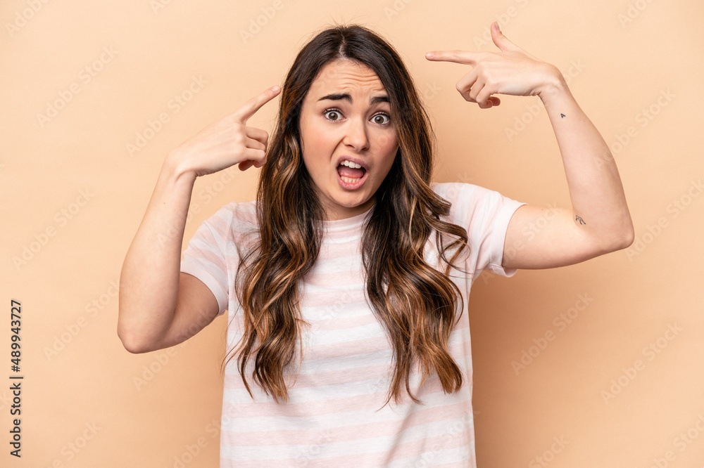 Young caucasian woman isolated on beige background showing a disappointment gesture with forefinger. Young caucasian woman isolated on beige background showing a disappointment gesture with forefinger.