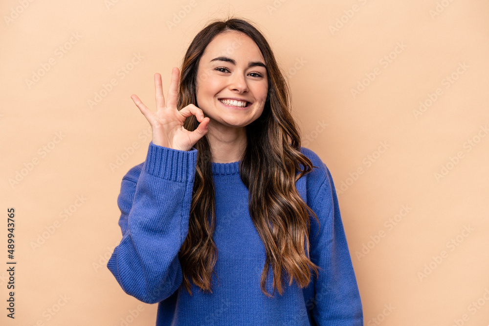 Fototapeta premium Young caucasian woman isolated on beige background cheerful and confident showing ok gesture.