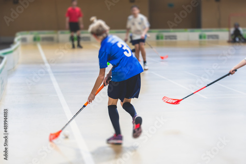 View of floorball match game, court hall indoor venue with junior teenage children school team playing in the background, floor ball hockey match game on arena stadium, copy space photo