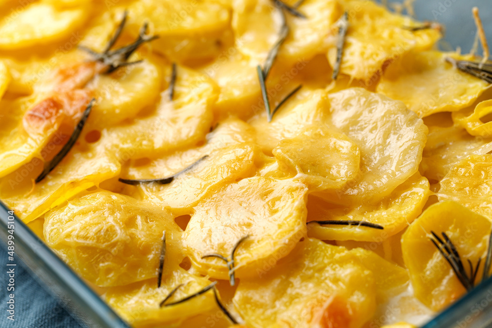 Potato gratin with rosemary and cheese in glass baking dish on blue napkin. Step-by-step recipe. Potato casserole