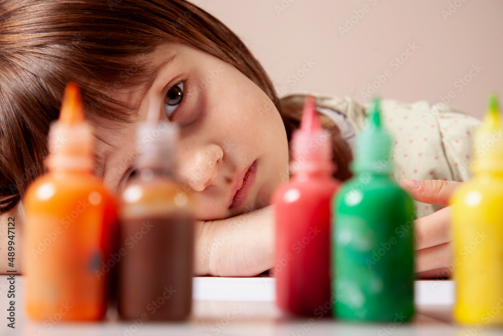 Portrait of young beautiful girl in front of multicolored paints. Art, childhood and creativity concept. Portrait of young beautiful girl in front of multicolored paints. Art, childhood and creativity concept.