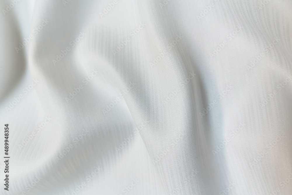White crumpled or wavy fabric texture background. Abstract linen cloth soft waves. Silk atlas or stretch jacquard. Smooth elegant luxury cloth texture. Concept for banner or advertisement.