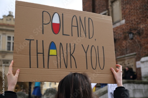 Poster with slogan POLAND THANK YOU and painted flags of Poland and Ukraine holds by woman while joins public demonstration to protest against Russian invasion photo