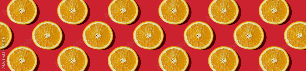 horizontal banner. Summer composition made from oranges, on dark red background. Creative Pattern made of slices of orange. horizontal banner. Summer composition made from oranges, on dark red background. Creative Pattern made of slices of orange.
