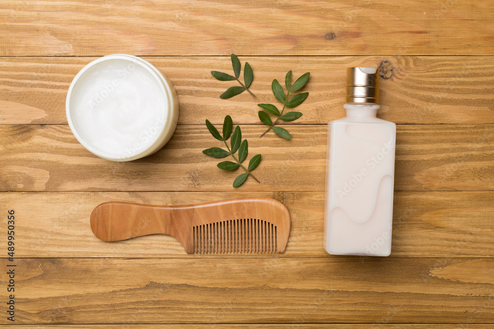 Shampoo and mask with herbal extract and comb on wooden background, top view Shampoo and mask with herbal extract and comb on wooden background, top view