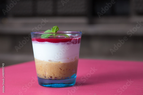 Tasty cheesecake in a glass cup on pink background